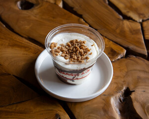 Dessert cup with crumble topping on a white plate on a wooden table