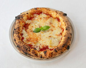 Traditional margherita pizza with melted mozzarella and basil on white plate for Italian cuisine visuals