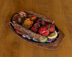 Indian mixed grill platter with seekh kebab, tandoori chicken, shrimp and vegetables served on sizzling plate