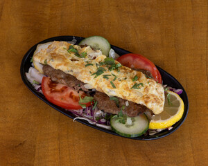 Kebab topped with omelette and served with fresh vegetables for fusion street food visuals
