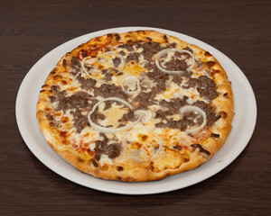 Overhead shot of a pizza with meat and onion rings on a white plate