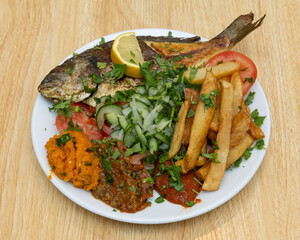 Grilled fish served with fries, lemon wedge and salad for traditional seafood meal visuals