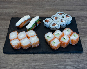 Various sushi rolls and nigiri on a black slate serving platter display