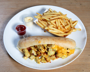 Close up of chicken sandwich with fries and sauces on a white plate