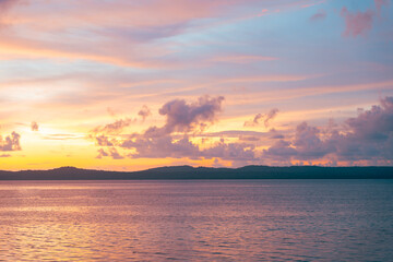 Peaceful sunset over ocean with soft hued clouds and calm water reflecting golden light.