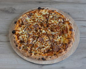 Overhead view of a sliced pizza with meat and cheese on a wooden board