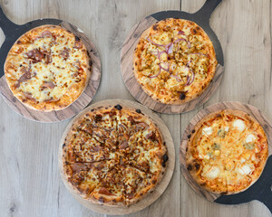 Overhead view of four pizzas on wooden boards with different toppings
