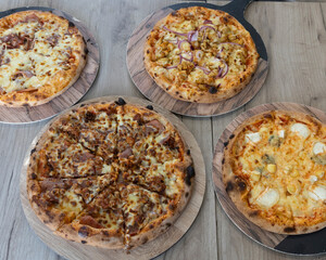 Overhead shot of four pizzas with different toppings on wooden boards