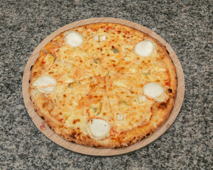 Overhead view of a cheese pizza with goat cheese on a wooden platter