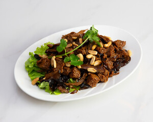 Plate of braised gluten with peanuts, cilantro and lettuce garnish