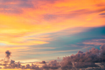 Colorful sunset view with radiant orange and pink clouds over a fading blue sky background.