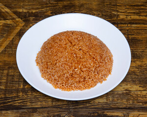 Close up of a plate of bulgur pilaf on a wooden textured surface