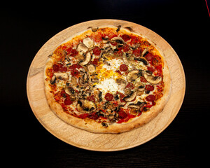 Overhead view of a mushroom and pepperoni pizza on a wooden plate