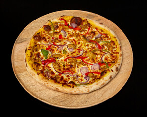 Overhead shot of a pizza with peppers and onions on a wooden plate