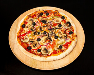 Overhead shot of a mushroom and olive pizza on a wooden serving board