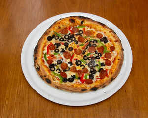 Overhead view of a pizza with pepperoni olives and bell peppers on plate
