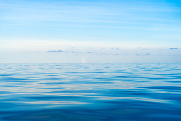 Tropical open sea with calm blue ocean waves and clear blue sky, perfect for summer vacation background.