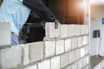 masonry worker make concrete wall by cement block and plaster at construction site 
