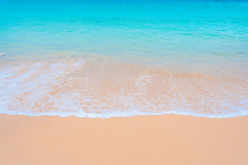Peaceful tropical coast with sparkling turquoise water and soft white sand under sunny skies.