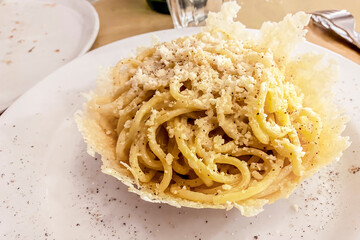 Tonnarelli cacio e pepe served in parmesan cheese basket, close-up