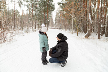 Fototapeta premium Dad and daughter walking and having fun in snowy winter forest