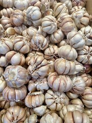 A close-up view of fresh garlic bulbs at a market, showcasing their natural texture, papery skin, and organic hues—perfect for culinary and agricultural themes.