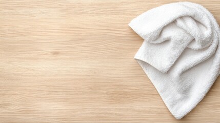 A white towel is folded on a light brown wooden surface.