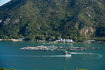 Aerial view of Lamma Island fishing village and floating fish farms in Hong Kong with surrounding green hills and boats on a sunny day