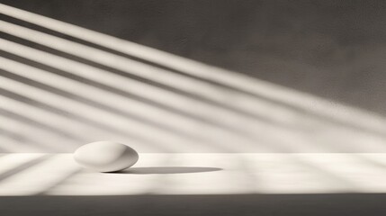 A white sphere sits on a white surface, casting a shadow on the wall behind it.