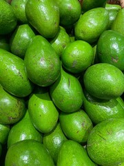 A vibrant display of fresh green avocados at a local market, highlighting their rich texture and natural appeal.