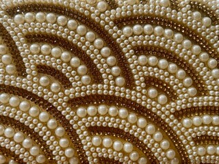 Close-up of intricate pearl and crystal bead embroidery in a wave-like pattern, showcasing detailed craftsmanship and luxury embellishment.