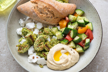 Grey plate with falafel, hummus, goat cheese and vegetable salad, horizontal shot, middle close-up, selective focus