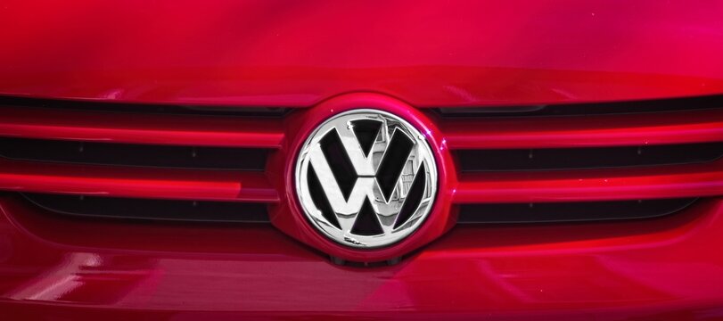 Neu-Ulm, Germany - April, 13, 2025: Closeup of a Volkswagen logo on the grille of a red car . Front view.