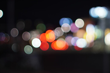 Out-of-focus shot of city lights at night, creating a soft and colorful bokeh effect. Urban illumination.