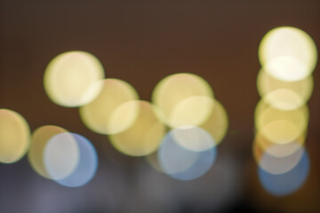 Abstract bokeh background with soft, blurred circles of warm yellow and cool white light against a dark, indistinct backdrop.