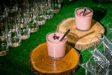 On a rustic wooden cutting board, two delicious glasses of pink smoothie are elegantly placed, ready to be enjoyed by anyone nearby