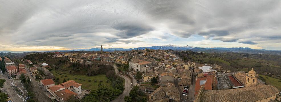 Wide angle aerial drone panoramic view of the ancient hilltop town of Atri in the province of Teramo, Abruzzo region, Italy. The historic center with its traditional terracotta roofs is surrounded by 