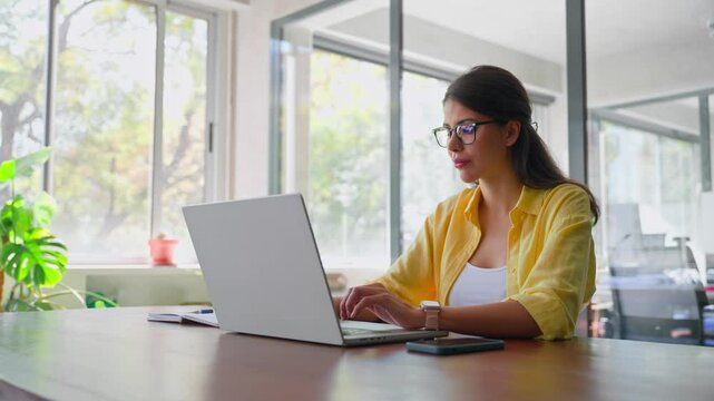 Female freelance entrepreneur working on online technological project on computer pc at company workplace. Focused young latin business woman, it specialist using laptop at work in office. Copy space