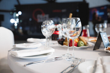 A beautifully arranged table is set elegantly with plates, utensils, fresh fruit, and wine glasses ready for a delightful meal experience