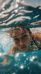 Young caucasian female swimming underwater with bubbles and reflections