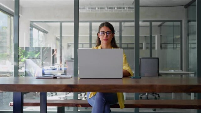 Thinking latin hispanic female marketing manager, professional specialist looking at screen working at laptop computer sitting in office. Young woman employee using pc for business. Wide, copy space