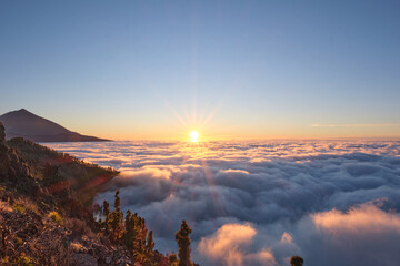 Breathtaking sunrise view over a sea of clouds in Teide National Park, Tenerife, Canary Islands. The silhouette of Mount Teide, Spain's highest volcano, rises in the background as morning light floods