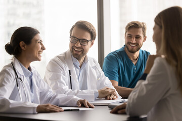 Fun and friendship at work. Young diverse medical staff polyethnic doctors interns engaged in...
