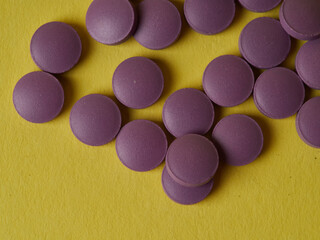lilac pills and medicinal vitamins in a package on a yellow background