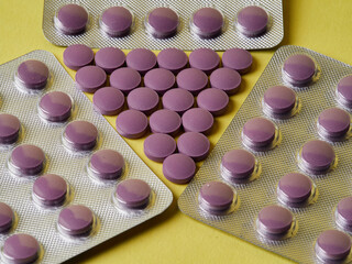lilac pills and medicinal vitamins in a package on a yellow background