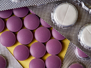 lilac pills and medicinal vitamins in a package on a yellow background