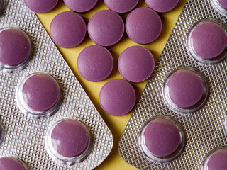 lilac pills and medicinal vitamins in a package on a yellow background