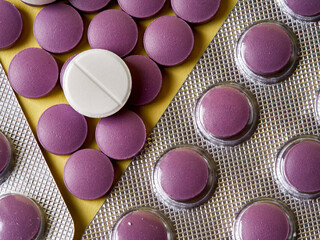 lilac pills and medicinal vitamins in a package on a yellow background