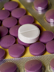 lilac pills and medicinal vitamins in a package on a yellow background