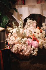 A beautiful basket filled with a variety of vibrant flowers is elegantly sitting on a table, enhancing the decor and ambiance